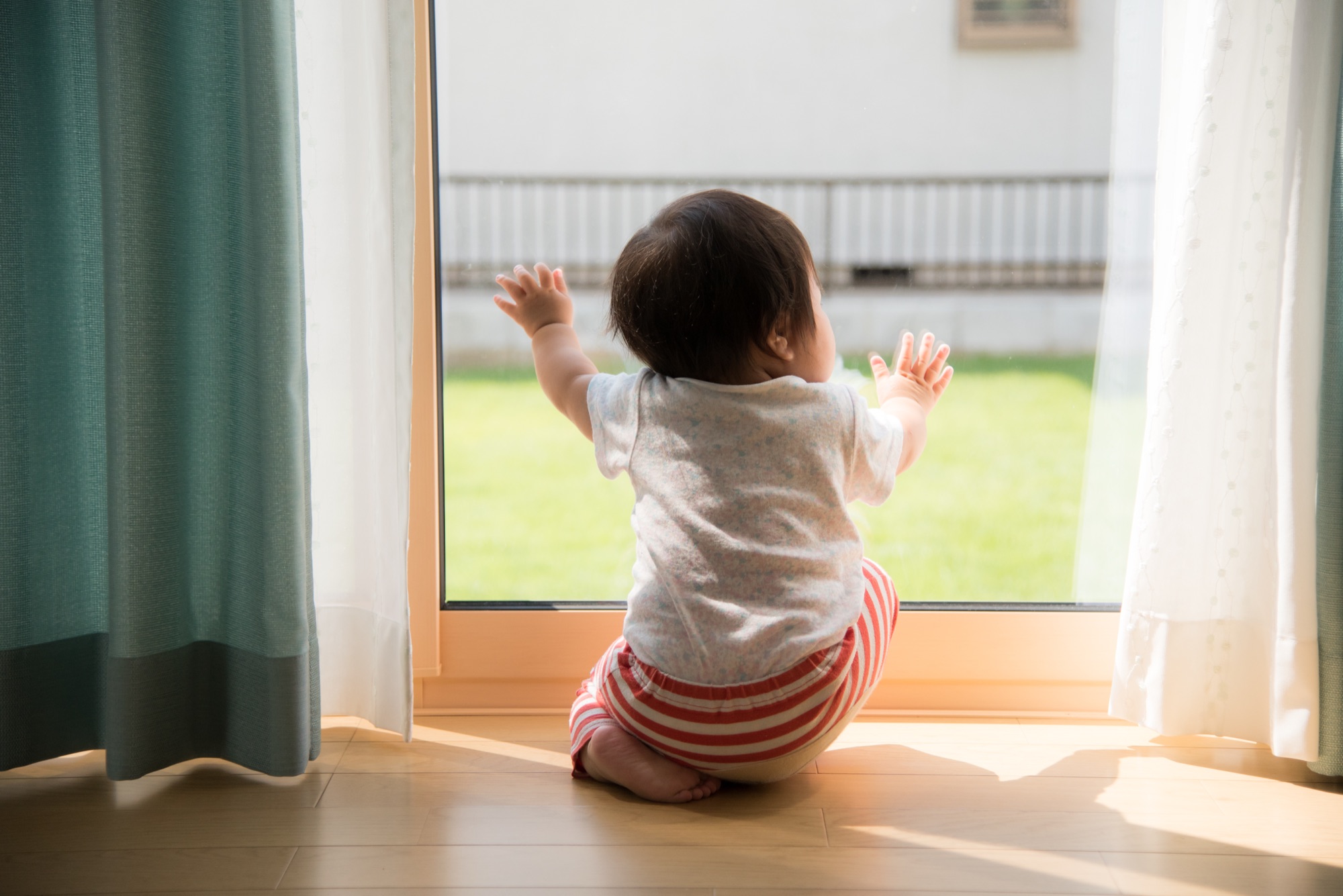 朝の光が差し込む窓辺の赤ちゃん