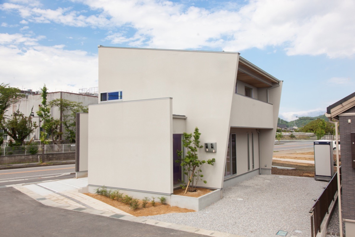白い塗り壁の外観と植栽のあるアプローチ